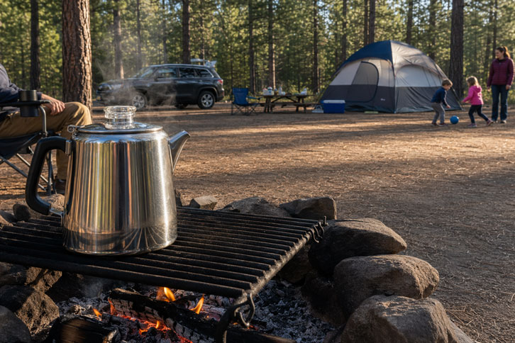 camping percolator on a campfire grate set up away from a play area for kids - How to Use a Camping Percolator (Step-by-Step Guide)