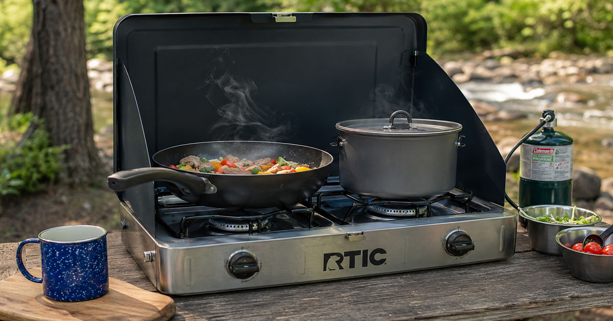2-burner propane camping stove set up on a table at a campsite