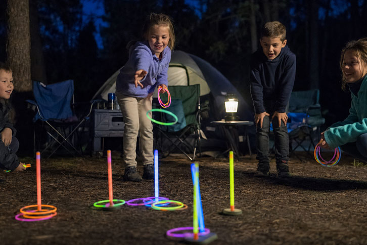 kids playing glow stick ring toss camping game - campfire games family