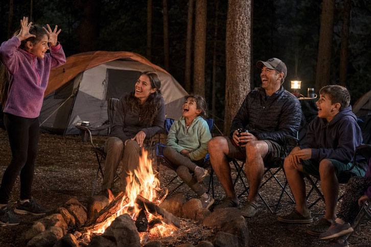 family playing camping charades around campfire