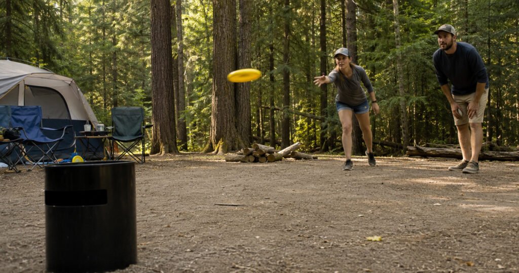 Family playing KanJam disc game at campsite