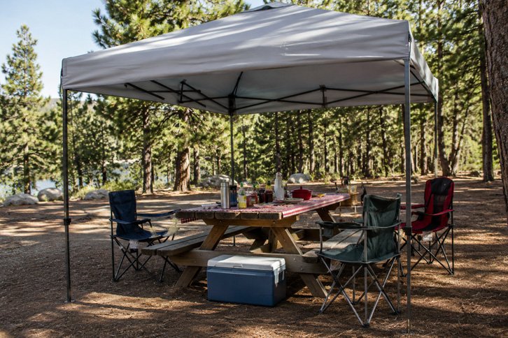 Camping canopy shading a table and chairs at a campsite