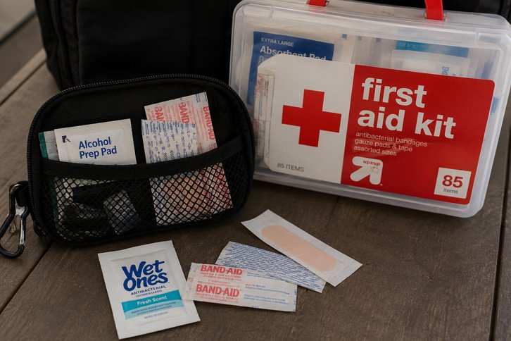 dollar store first aid supplies next to a full camping first aid kit - dollar store camping hacks