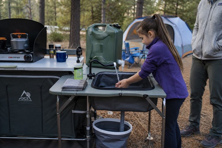 Child washing hands at a camp kitchen sink station